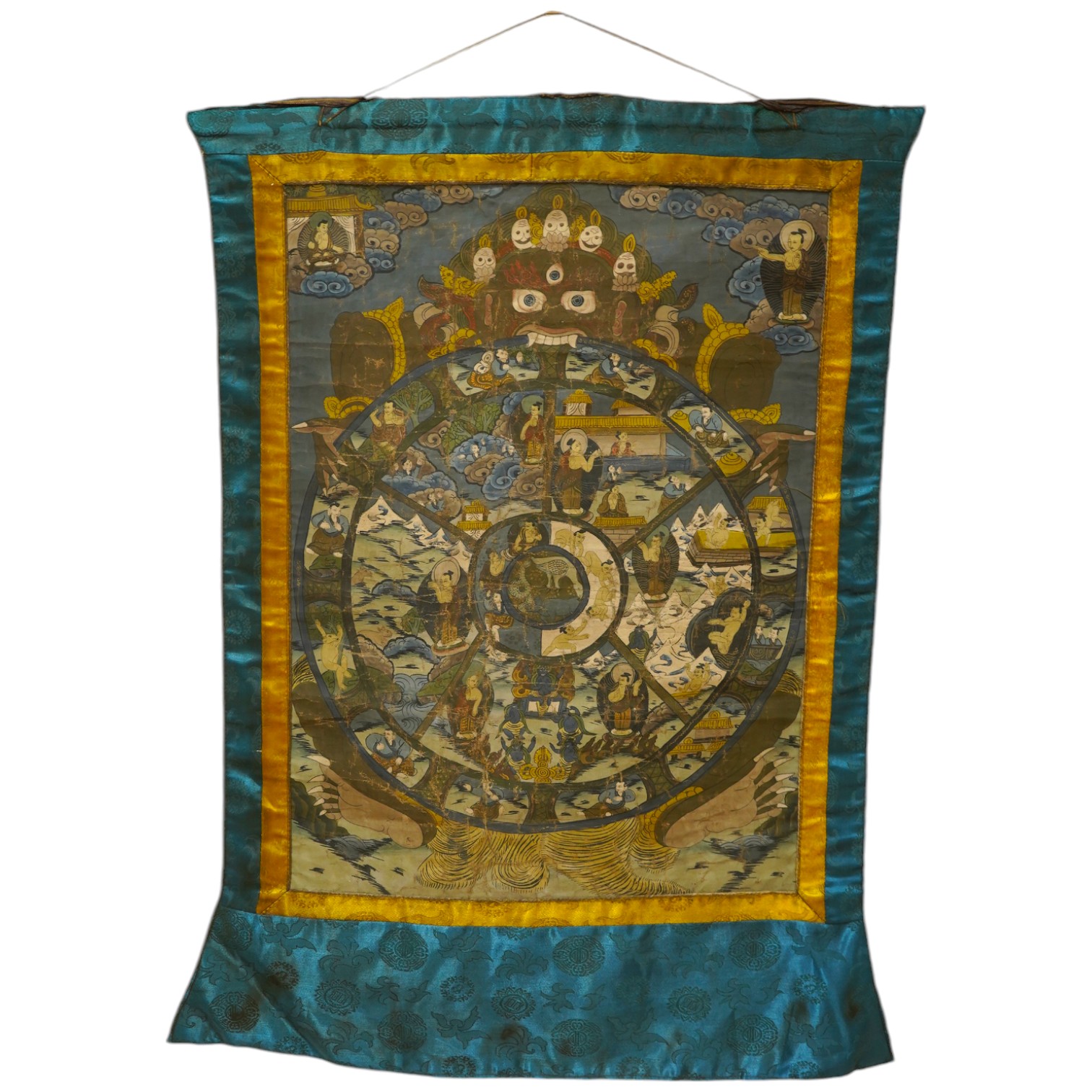 A 20th century Tibetan ‘Wheel of Life’ hand painted damask bordered Thangka, depicting the complex mandala of the circle of existence of beings in Buddhist philosophy, it depicts the teachings of Shakyamuni Buddha, showi